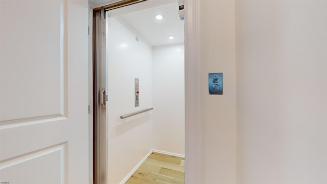 interior details featuring elevator and hardwood / wood-style floors