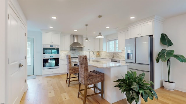 kitchen with wall chimney exhaust hood, white cabinetry, and stainless steel appliances