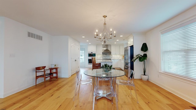 dining area with plenty of natural light, a chandelier, and light wood-type flooring