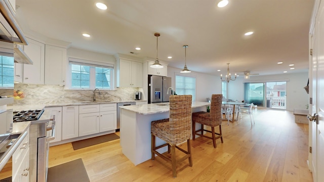 kitchen with a center island, white cabinets, stainless steel appliances, and light hardwood / wood-style floors