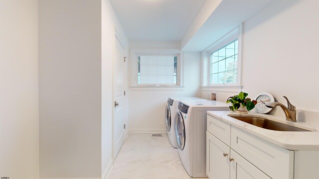 laundry area featuring cabinets, washing machine and dryer, and sink