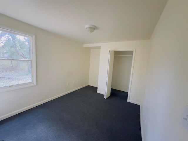 unfurnished bedroom with dark colored carpet and a closet