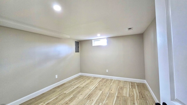 empty room featuring electric panel and light hardwood / wood-style flooring