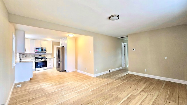 unfurnished living room with sink and light wood-type flooring