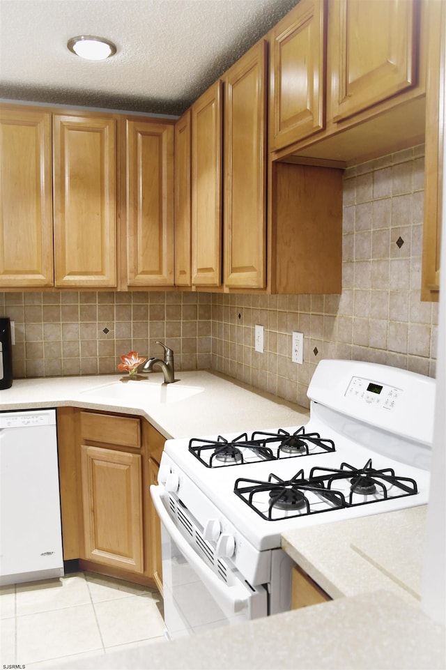 kitchen with white appliances, backsplash, sink, light tile patterned floors, and a textured ceiling