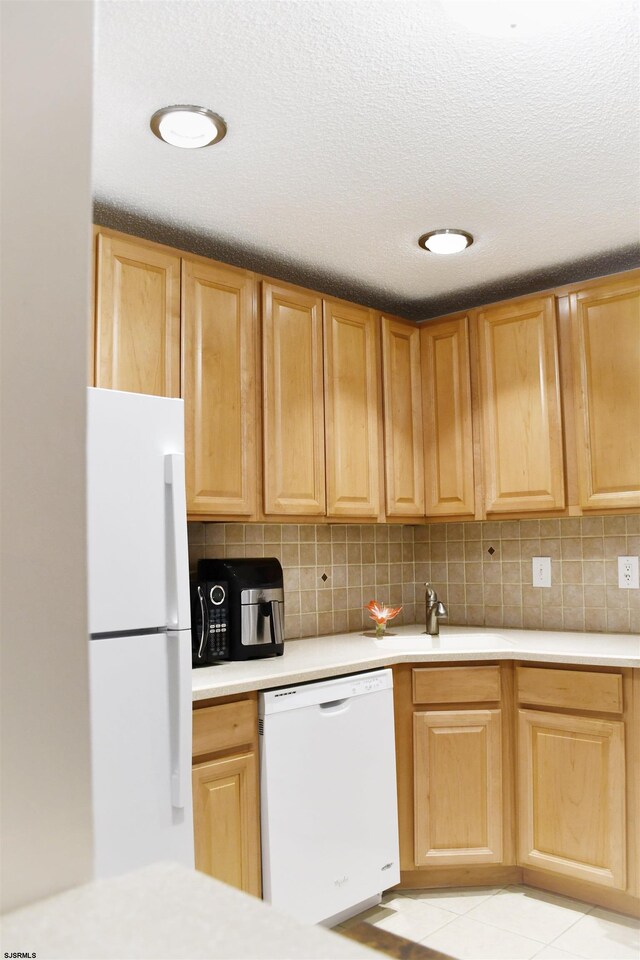 kitchen featuring tasteful backsplash, sink, light tile patterned floors, and white appliances