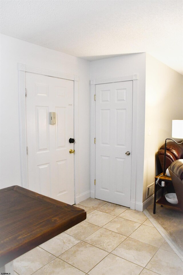 entrance foyer with a textured ceiling and light tile patterned flooring