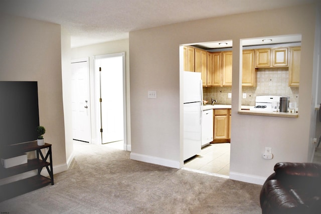 kitchen featuring light brown cabinetry, white appliances, light colored carpet, and backsplash