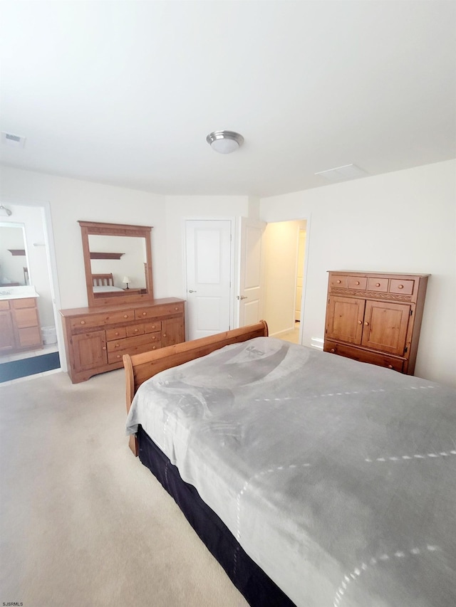 bedroom featuring ensuite bath and light carpet