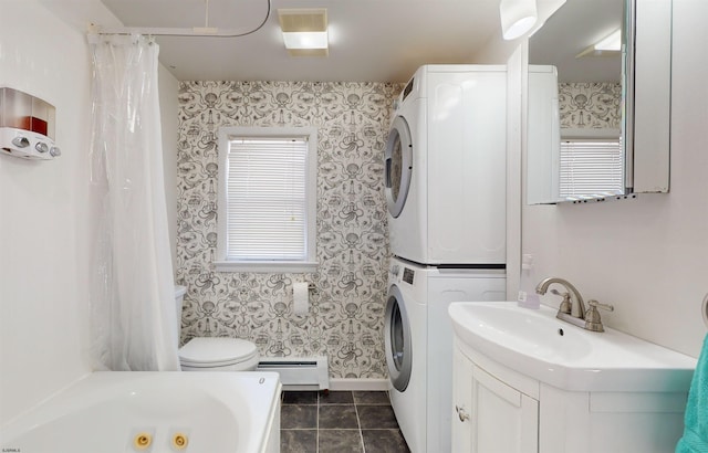 bathroom featuring a tub to relax in, vanity, a baseboard heating unit, stacked washer / dryer, and tile patterned flooring