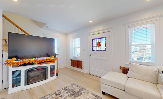 living room featuring radiator, light hardwood / wood-style floors, and a wealth of natural light