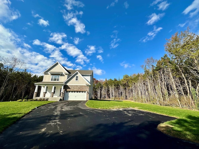 view of front of property featuring a front lawn, covered porch, and a garage