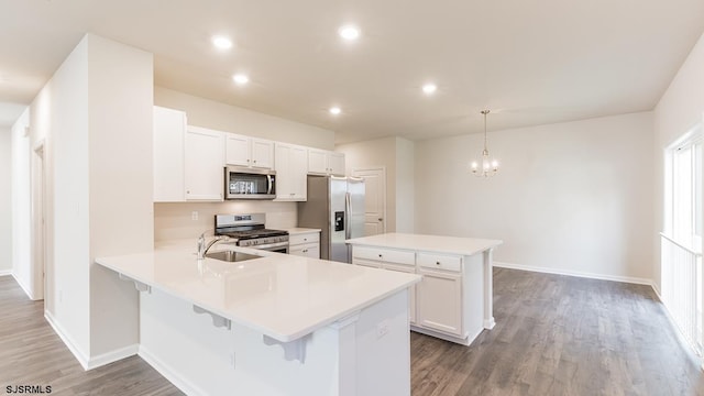 kitchen with white cabinets, hanging light fixtures, dark hardwood / wood-style flooring, kitchen peninsula, and stainless steel appliances