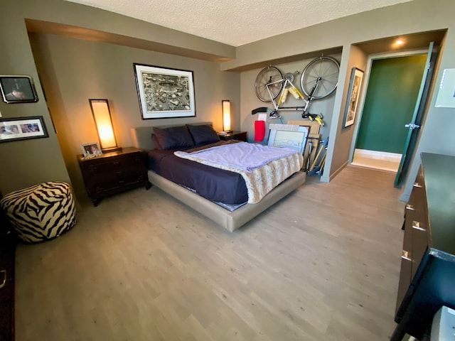 bedroom with a textured ceiling and light hardwood / wood-style flooring