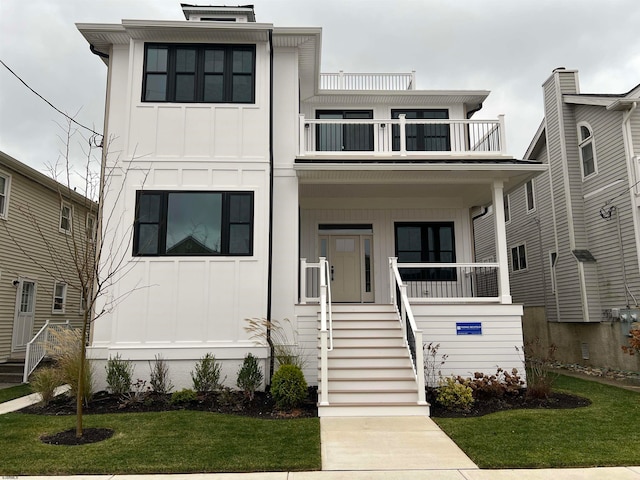 view of front of property featuring a balcony, covered porch, and a front yard