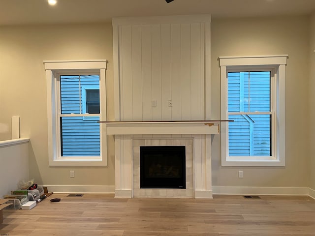 unfurnished living room with a tile fireplace and light wood-type flooring