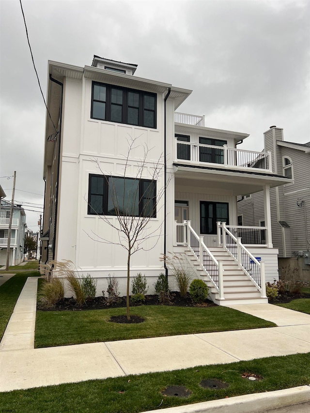 view of front of house featuring a front lawn, a balcony, and covered porch