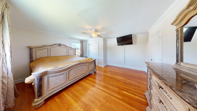 bedroom featuring a closet, light hardwood / wood-style flooring, ceiling fan, and ornamental molding