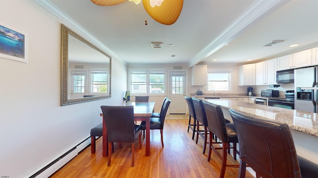 dining room with light hardwood / wood-style floors, baseboard heating, crown molding, and ceiling fan