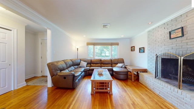 living room with a fireplace, light hardwood / wood-style floors, and crown molding