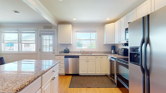 kitchen with appliances with stainless steel finishes, white cabinetry, and light hardwood / wood-style flooring