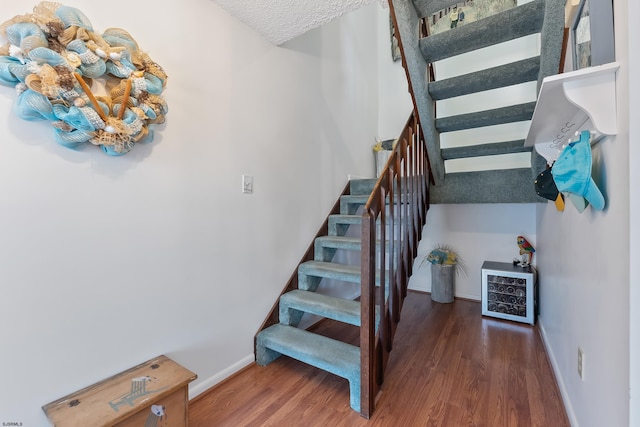 stairs with wood-type flooring and a textured ceiling