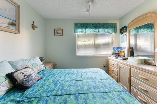 bedroom featuring multiple windows, ceiling fan, and a textured ceiling