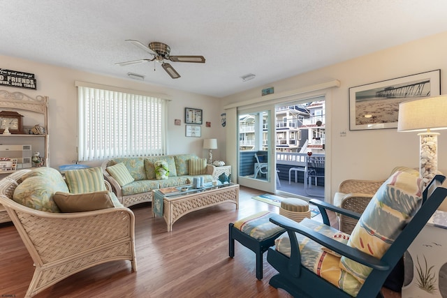 living room with hardwood / wood-style flooring, ceiling fan, and a textured ceiling