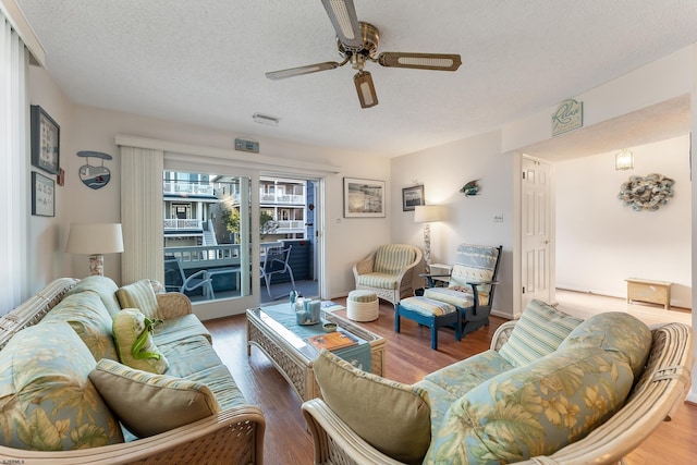 living room with ceiling fan, a textured ceiling, and hardwood / wood-style flooring