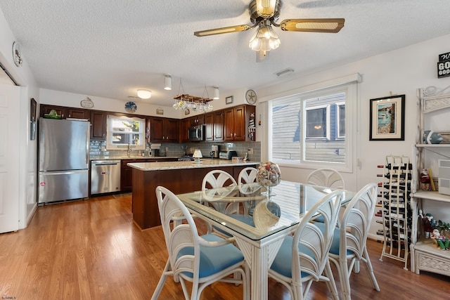 dining area with a textured ceiling, light hardwood / wood-style floors, and ceiling fan