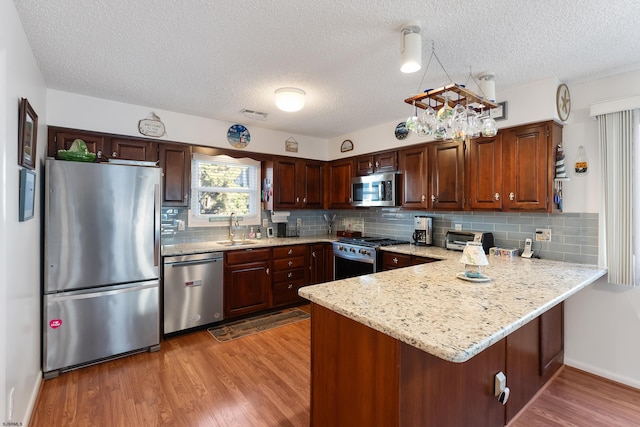 kitchen with a textured ceiling, sink, wood-type flooring, and stainless steel appliances