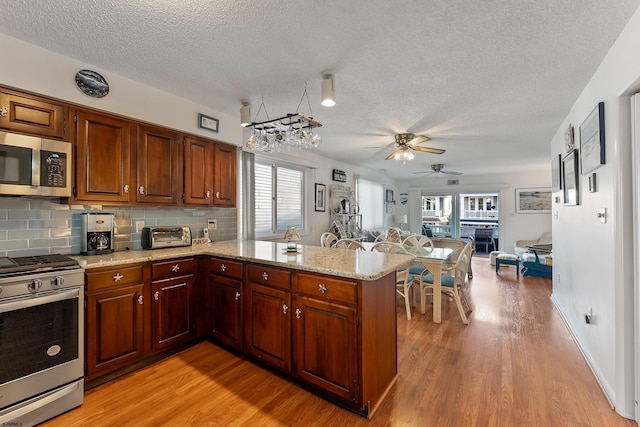 kitchen featuring kitchen peninsula, light wood-type flooring, stainless steel appliances, and a healthy amount of sunlight