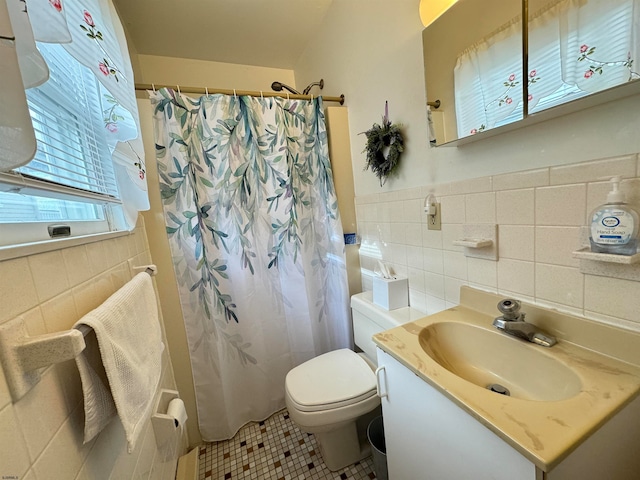 bathroom featuring tile walls, vanity, toilet, and walk in shower