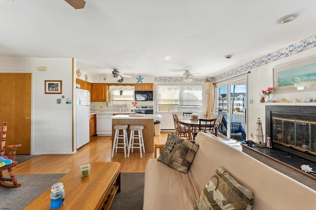 living room featuring light hardwood / wood-style flooring, sink, plenty of natural light, and ceiling fan