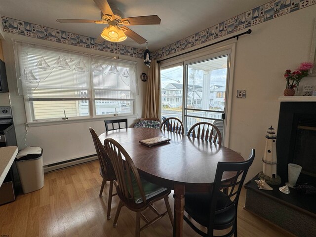 dining room with a baseboard heating unit, light hardwood / wood-style flooring, and ceiling fan