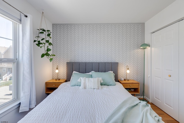 bedroom featuring hardwood / wood-style floors, a closet, and multiple windows