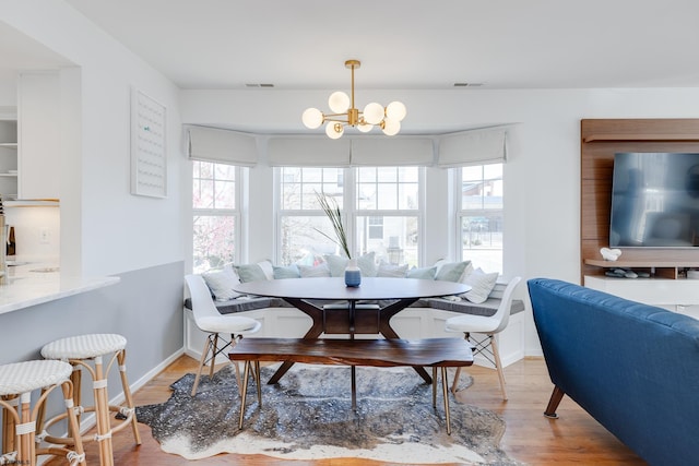 dining space with wood-type flooring and an inviting chandelier