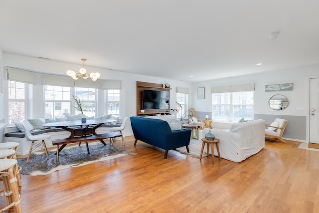 living room with light hardwood / wood-style floors, plenty of natural light, and a notable chandelier