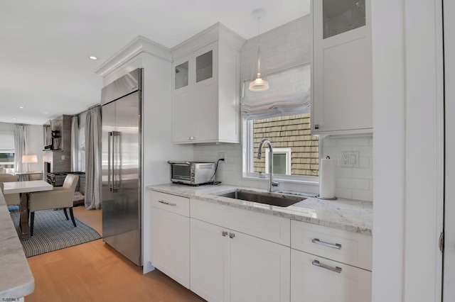 kitchen featuring white cabinets, sink, decorative backsplash, light hardwood / wood-style floors, and stainless steel built in refrigerator