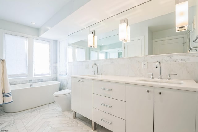 bathroom with decorative backsplash, vanity, a tub to relax in, and toilet