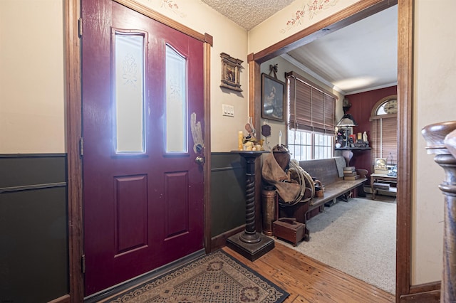 entrance foyer with a textured ceiling, hardwood / wood-style flooring, and ornamental molding