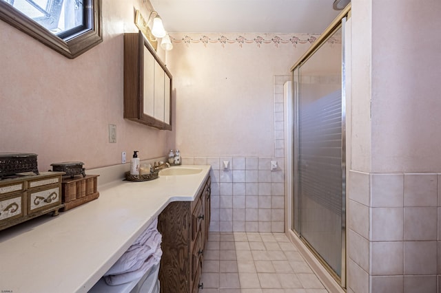 bathroom featuring vanity, tile patterned floors, a shower with door, and tile walls