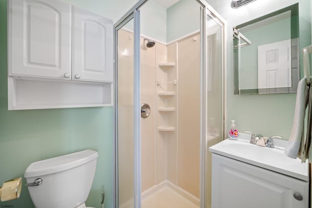 bathroom with vanity, toilet, and a shower with door