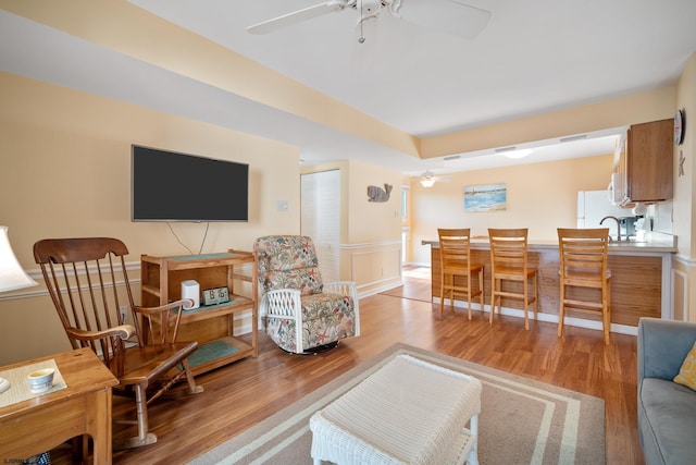 living room with ceiling fan, sink, and wood-type flooring