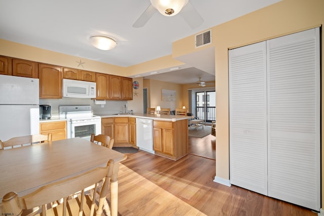 kitchen featuring white appliances, sink, light hardwood / wood-style flooring, ceiling fan, and kitchen peninsula