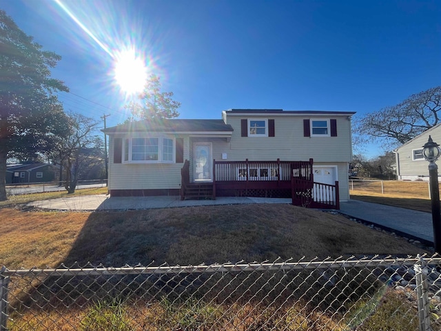 tri-level home with a front yard, a garage, and a deck