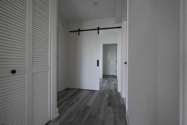 corridor with dark hardwood / wood-style flooring and a barn door