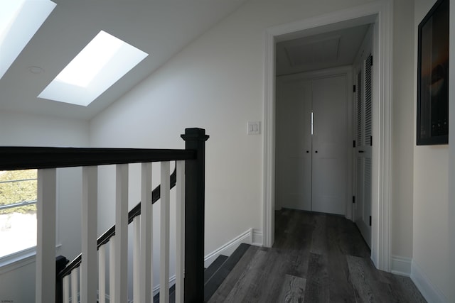 hallway featuring dark wood-type flooring and lofted ceiling with skylight