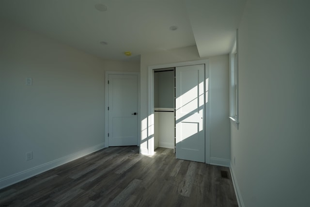 unfurnished bedroom with a closet and dark hardwood / wood-style floors