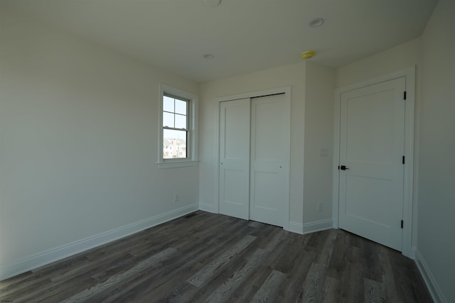 unfurnished bedroom featuring a closet and dark wood-type flooring